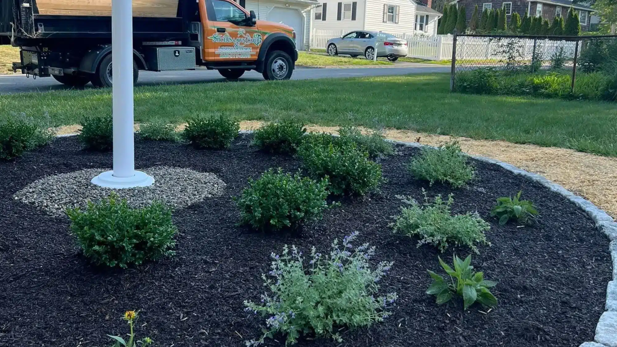 lawn-care-services-waterford-ct Professionally landscaped residential yard in Waterford featuring fresh mulch, shrubs, garden edging, and healthy green lawn maintained by a lawn care company.