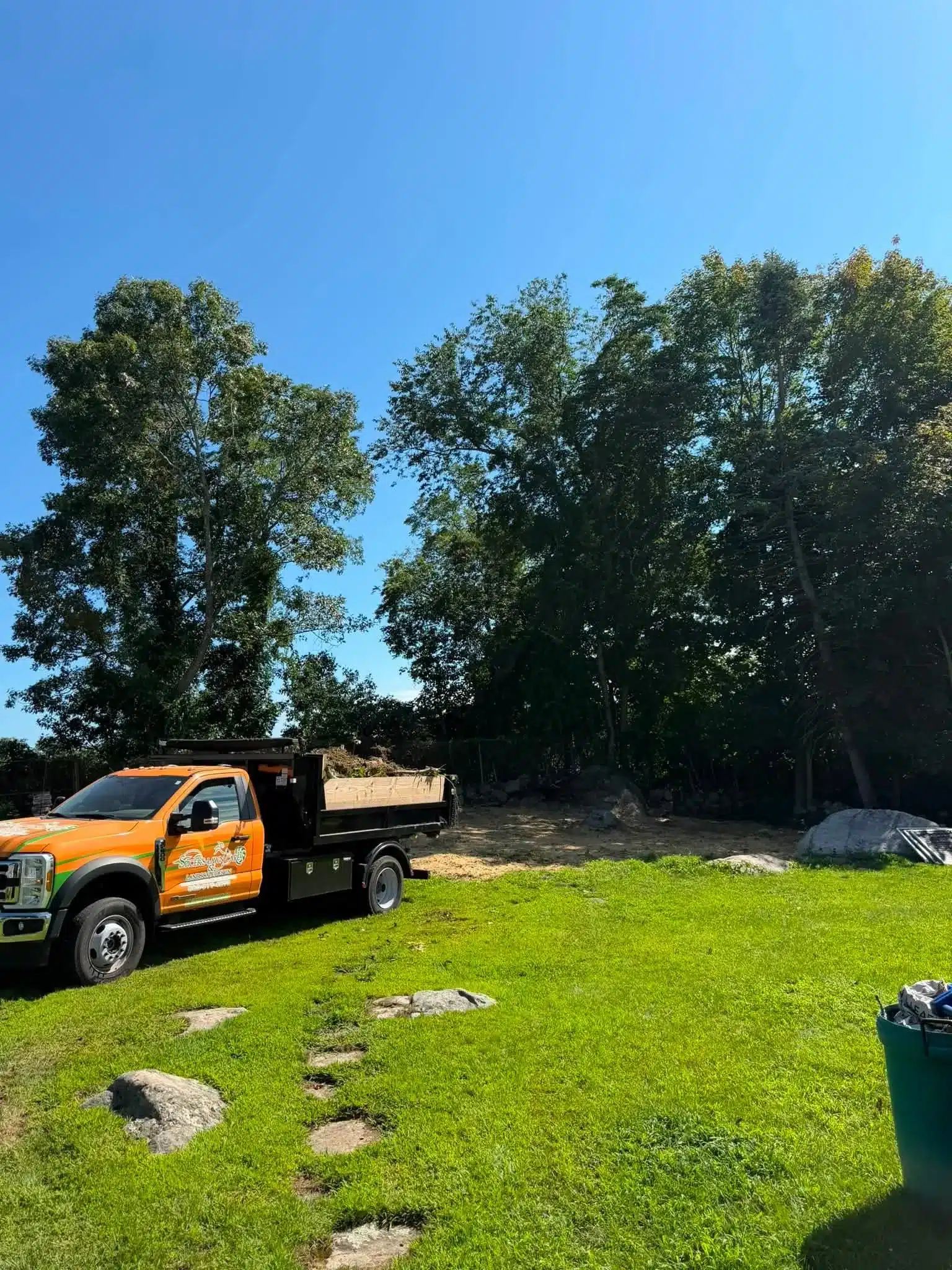 Completed stump removal and expanded backyard landscape beds in Groton, CT by Spicers Lawn Care & Landscape Design.