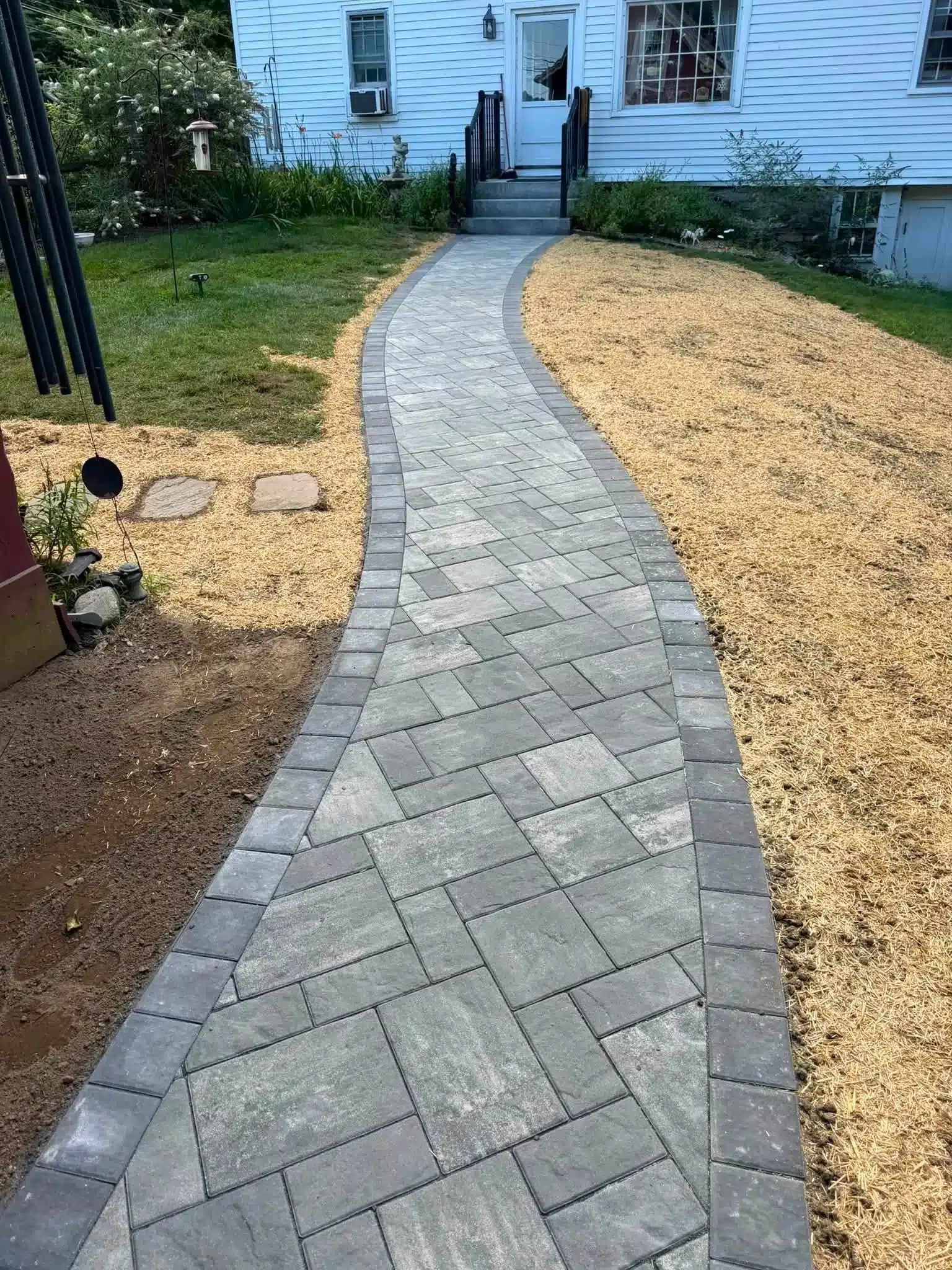 Unilock walkway installation adding a polished and durable pedestrian path to a Preston, CT landscape.