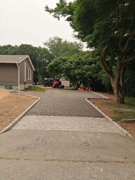 Crushed stone driveway installation in Waterford, CT, featuring a decorative cobblestone apron, stone edging, and residential hardscaping by Spicer's Lawn Care.