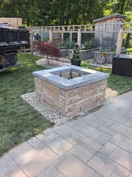 Custom stone fire pit installation in Uncasville, CT, featuring a square block fire pit, decorative stone border, and paver patio by Spicer's Lawn Care.