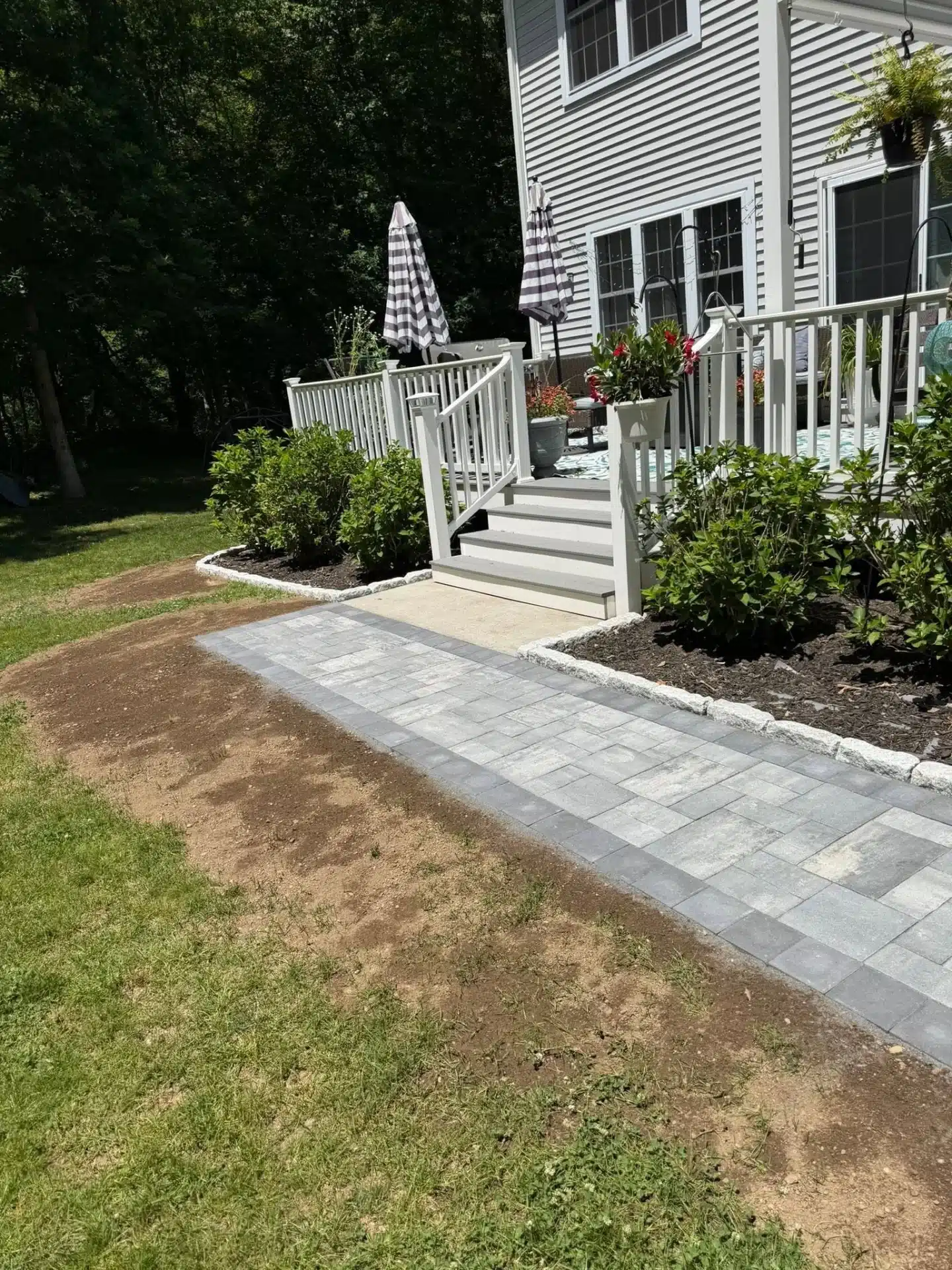 hardscaping-services-waterford-ct-spicers-lawn-care (3) Residential hardscaping in Waterford, CT, showcasing a spacious curved paver patio extending toward a landscaped backyard.